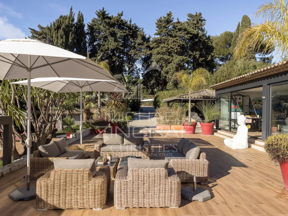Wooden terrace with garden furniture and parasols, overlooking the garden and swimming pool in Cannes.