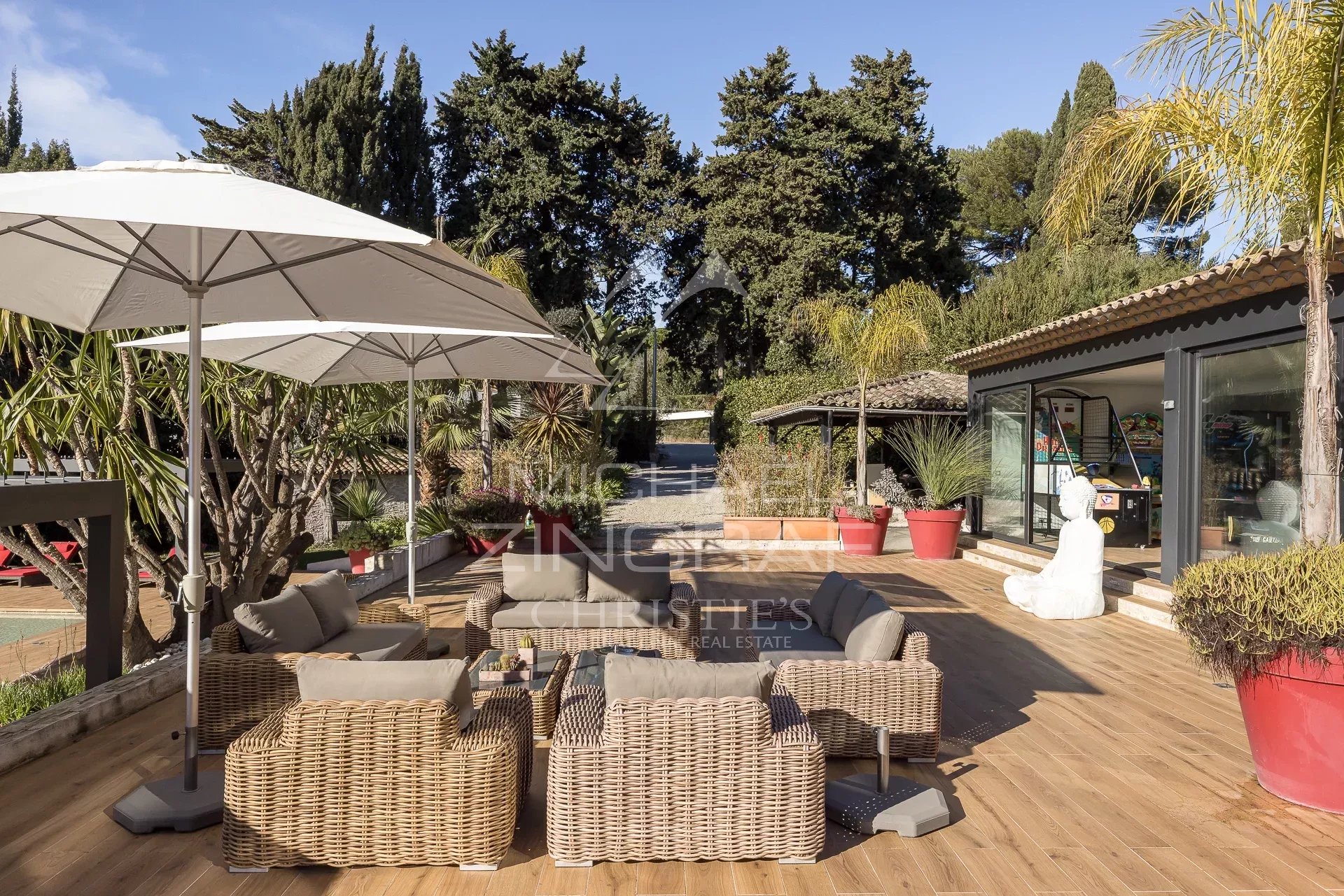 Terrace with a view in Cannes Wooden terrace with garden furniture and parasols, overlooking the garden and swimming pool in Cannes.