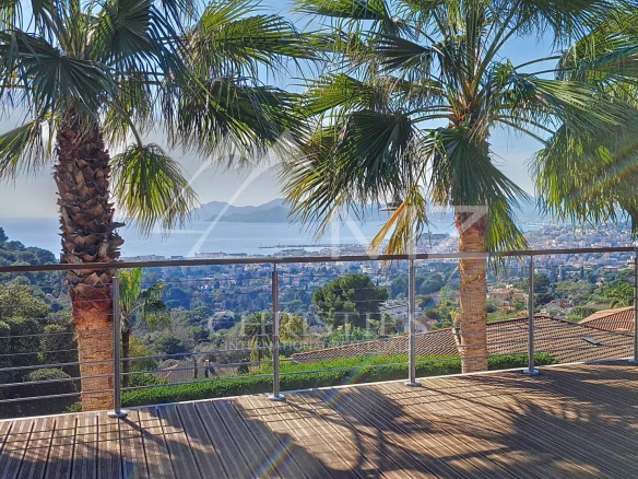 Terrace of a villa in Cannes with views of the sea and palm trees.