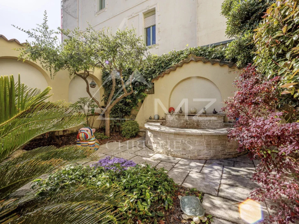 Jardin d'une maison de pécheurs avec fontaine et végétation à Cannes Palm Beach.