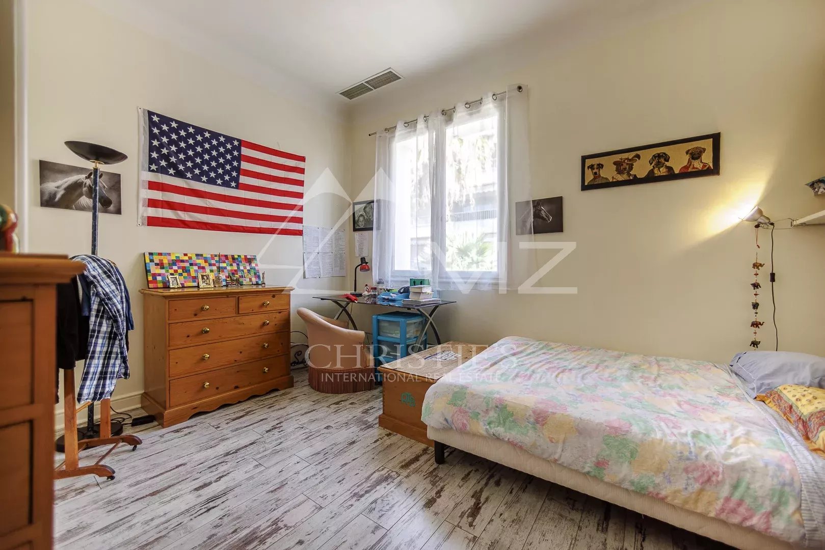 Chambre d'une maison de pêcheurs à Cannes avec un drapeau américain et un lit simple.