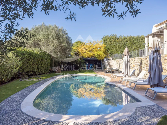 Vue d'une piscine entourée de transats et de verdure dans une propriété au Cannet, avec un ciel dégagé.