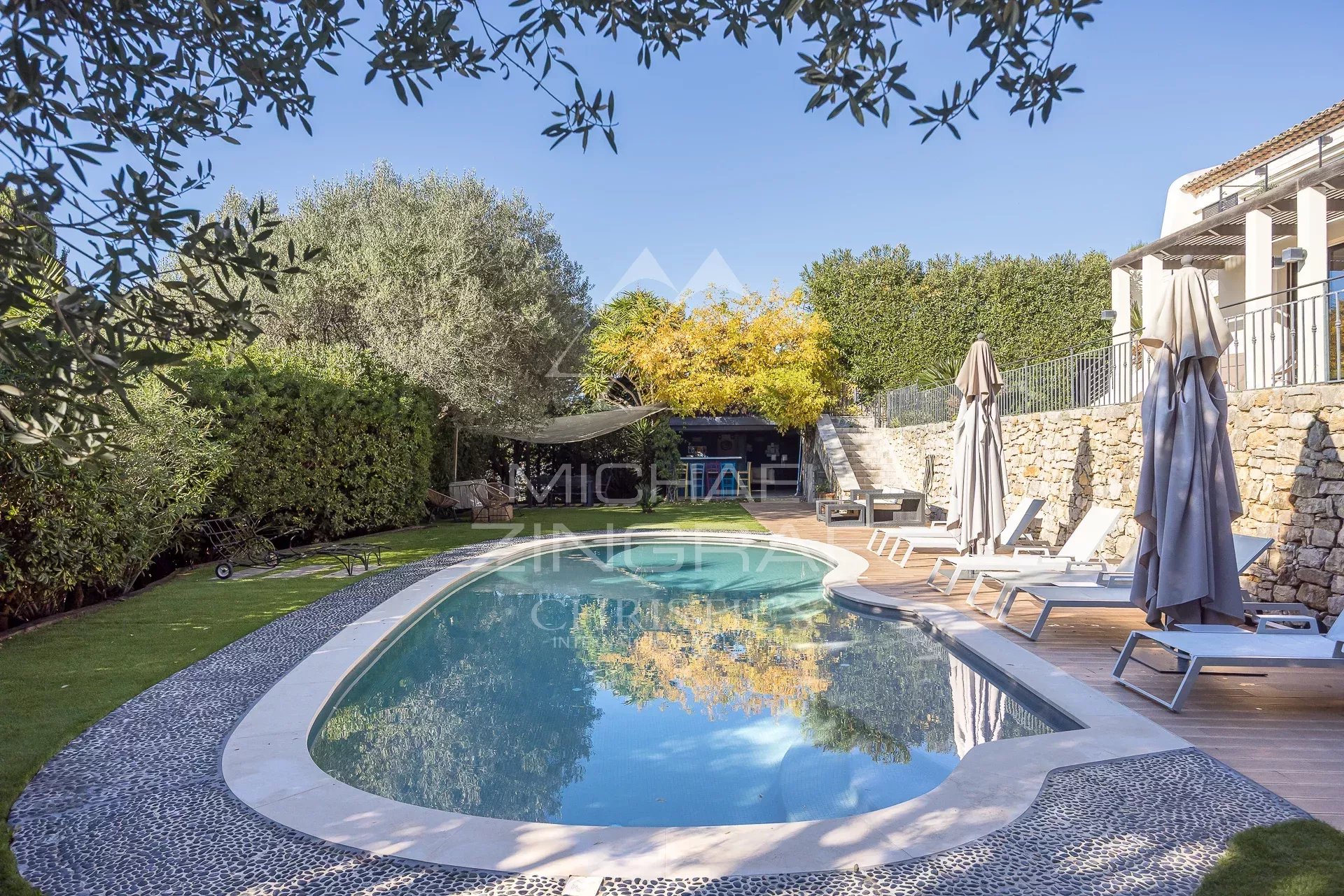 Piscine dans une propriété au Cannet Vue d'une piscine entourée de transats et de verdure dans une propriété au Cannet, avec un ciel dégagé.