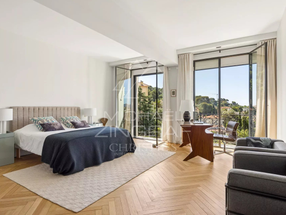 Chambre lumineuse avec balcon, vue sur le jardin, mobilier moderne et parquet en bois.