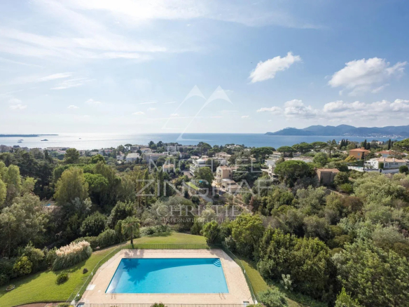 Vue panoramique sur la Méditerranée depuis un penthouse à Cannes, avec piscine et verdure.
