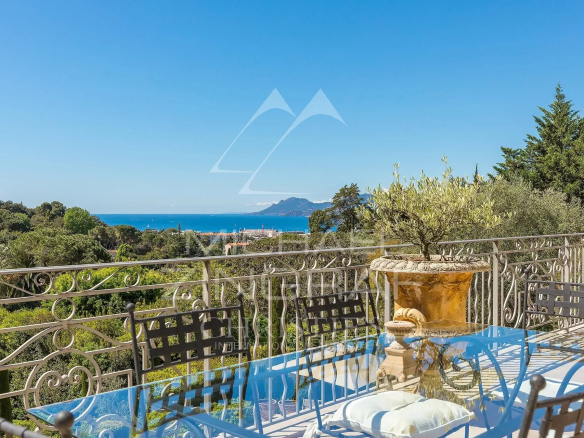 Vue sur la baie de Cannes depuis une terrasse avec mobilier de jardin.