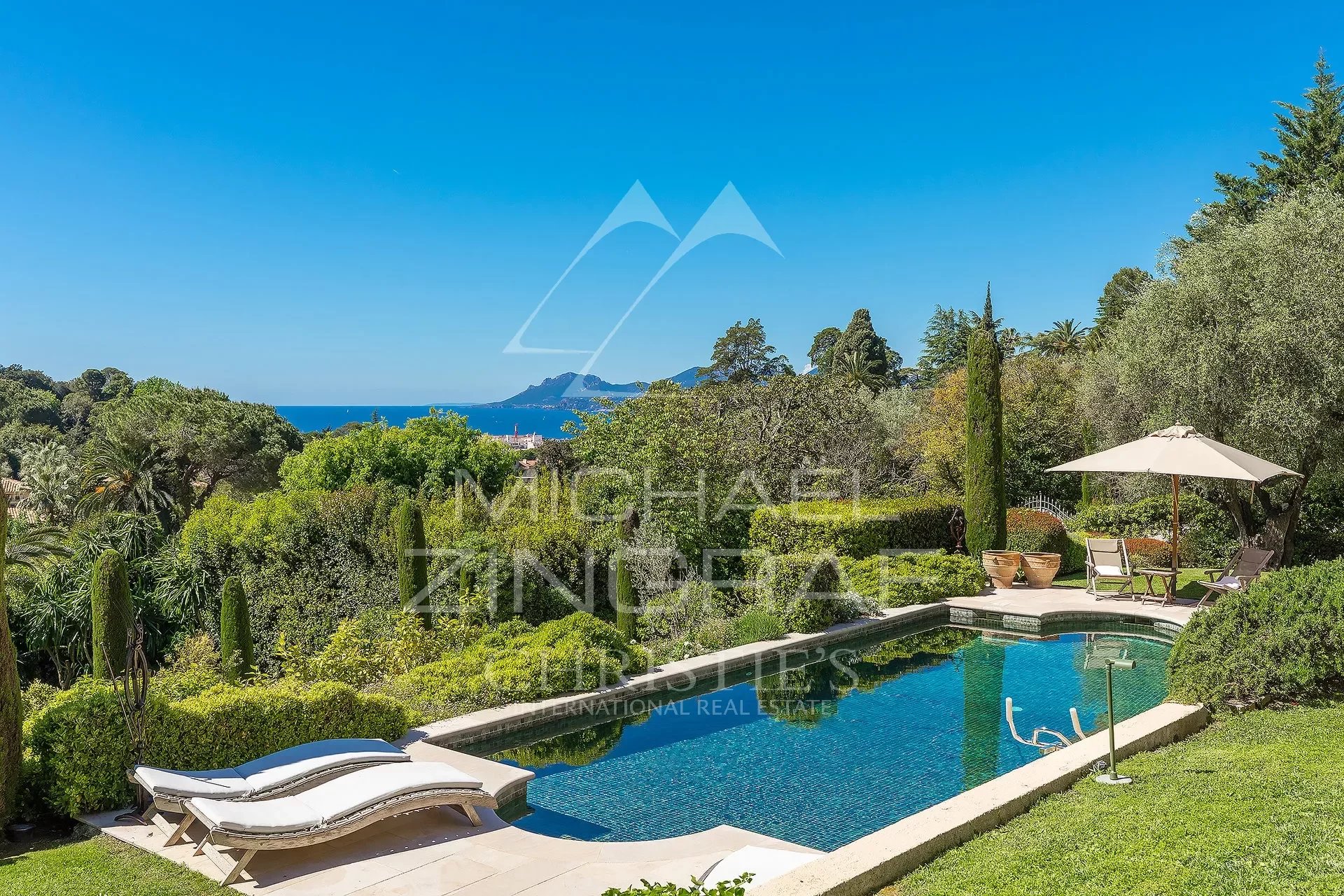 Propriété de style toscan à Cannes Vue sur une piscine et un jardin paysager avec la baie de Cannes en arrière-plan.