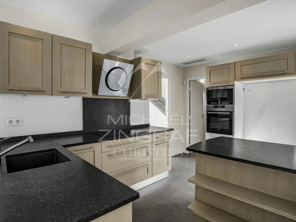 Cuisine moderne dans une villa à Cannes, avec des meubles en bois clair et un plan de travail en granit.