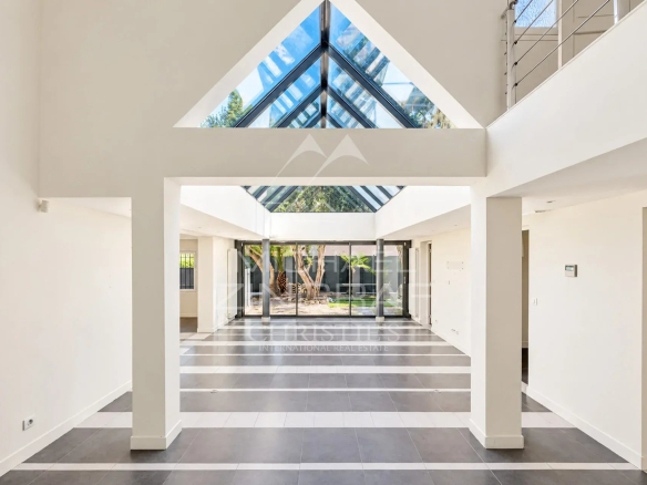 Intérieur d'une villa moderne avec un grand espace ouvert et une verrière au plafond.