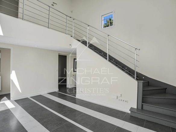 Intérieur d'une villa moderne avec un escalier en colimaçon et de grandes fenêtres.
