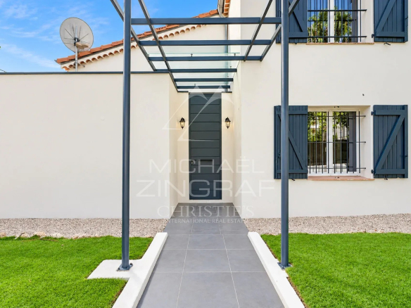 Entrée d'une villa moderne avec un chemin en dalles et un auvent en verre.