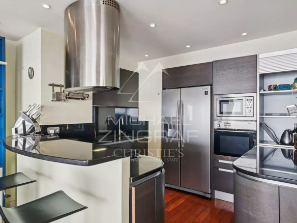 Modern kitchen with bar and stainless steel equipment in an apartment in Cannes.