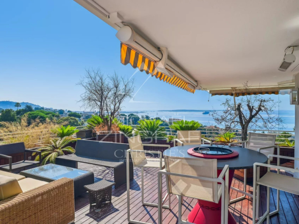 Sunny terrace with panoramic sea views in Cannes, garden furniture and vegetation.