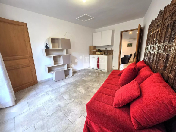 Intérieur d'une villa à Baudinard-sur-Verdon avec canapé rouge et cuisine ouverte.