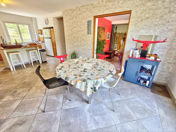 Intérieur d'une villa avec une table ronde et des chaises, décor moderne et lumineux.