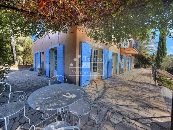 Provençal country house with terrace and blue shutters in Lorgues, surrounded by greenery.