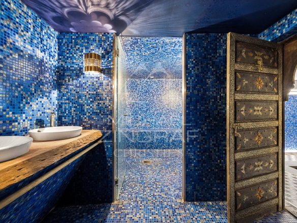 Salle de bains moderne avec carrelage bleu et douche en verre, décorée de bois et de métal.