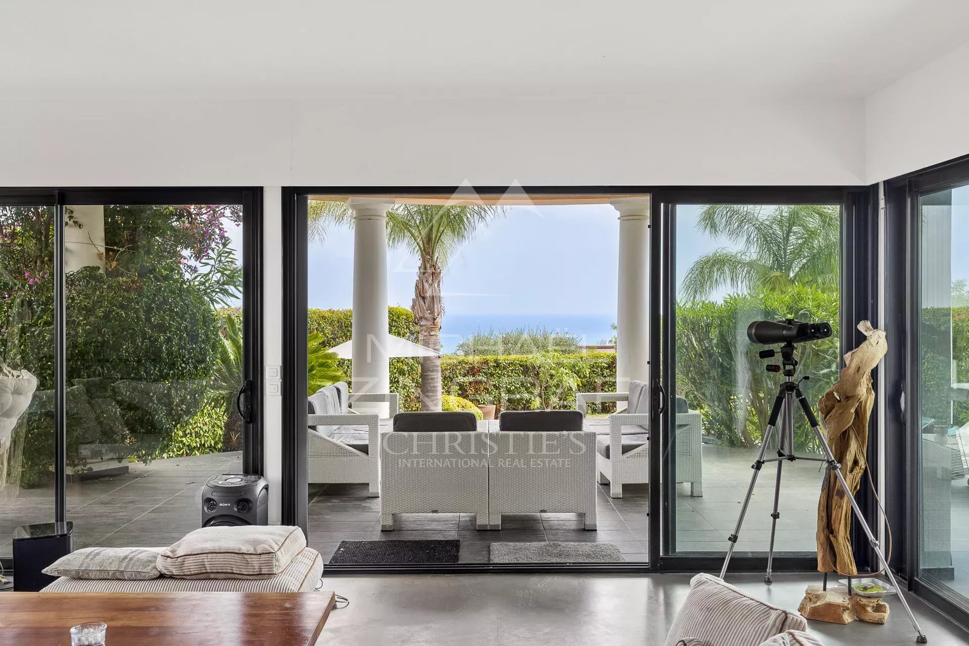 Vue intérieure d'une villa contemporaine avec accès à une terrasse et vue sur la mer.