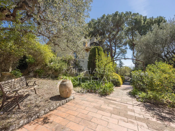 Jardin d'une bastide du XVIIIe siècle à Nice avec des arbres et des chemins en pierre.