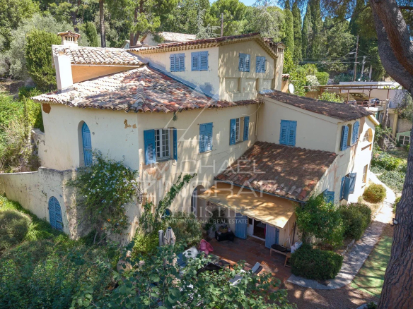 Bastide du XVIIIᵉ siècle à Nice, avec façade en pierre et volets bleus, entourée de verdure.