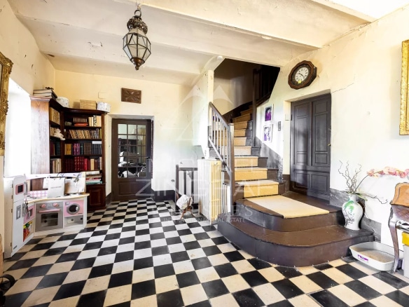 Intérieur d'une bastide du XVIIIᵉ siècle avec un hall d'entrée et un escalier en bois.