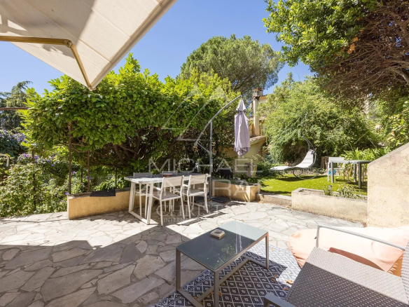 Terrasse en pierre avec mobilier de jardin dans un jardin verdoyant d'une bastide du XVIIIe siècle à Nice.