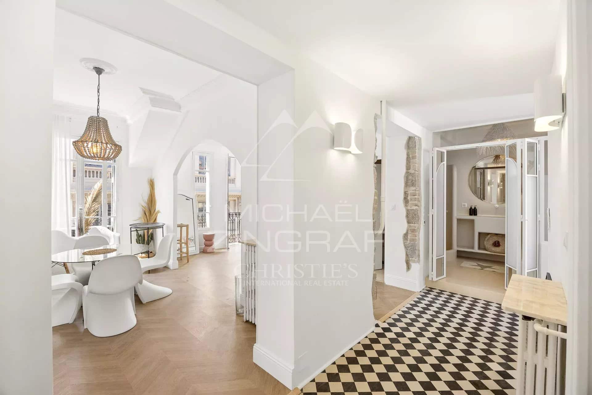 Intérieur d'un appartement au dernier étage avec décoration bohème chic, lumière naturelle et vue sur la mer.