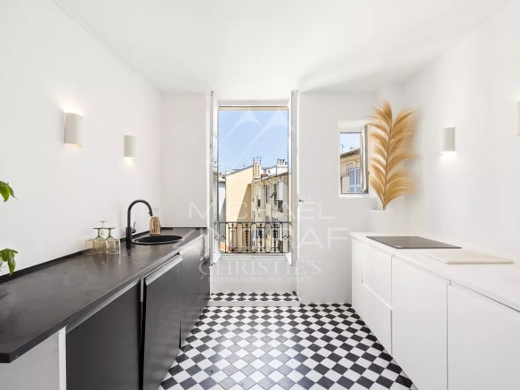Cuisine moderne avec carrelage noir et blanc et vue sur les toits de Nice.