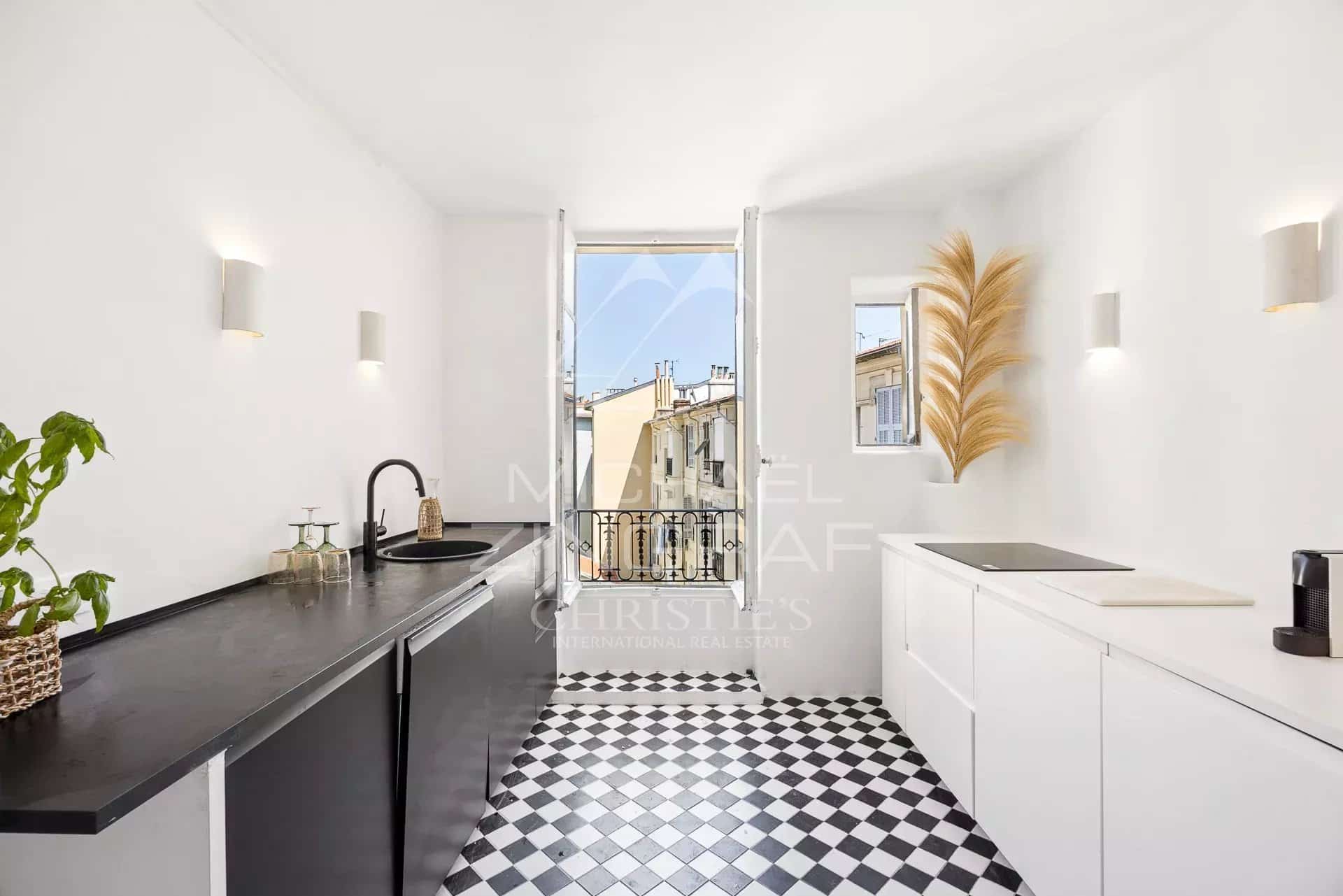 Cuisine moderne avec carrelage noir et blanc et vue sur les toits de Nice.