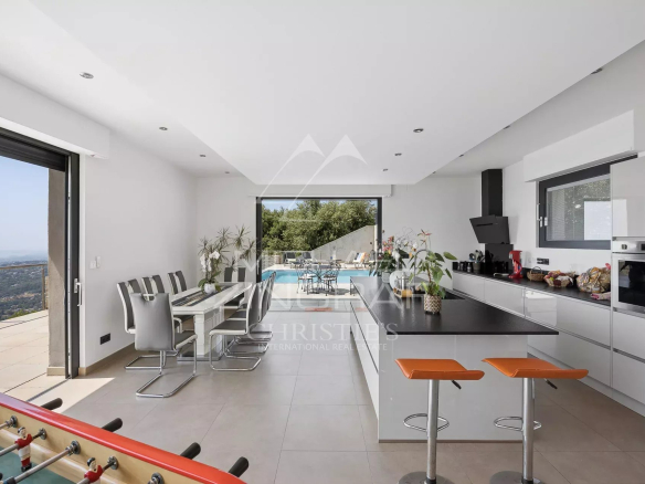 Intérieur d'une villa moderne avec cuisine ouverte et vue sur la mer.