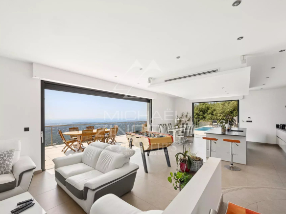 Intérieur d'une villa moderne avec vue sur la mer, espace lumineux et mobilier contemporain.