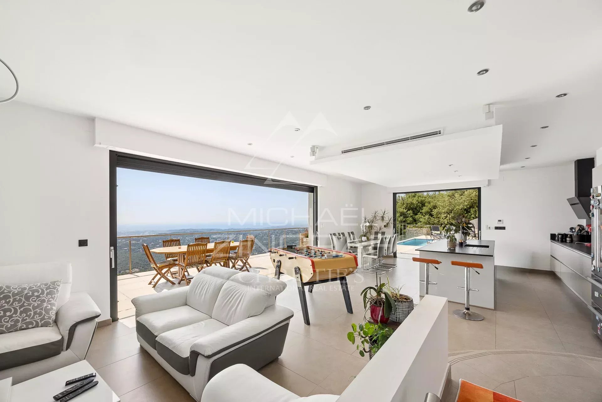 Intérieur d'une villa moderne avec vue sur la mer, espace lumineux et mobilier contemporain.