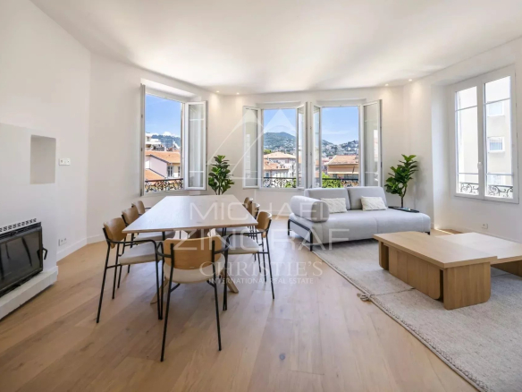 Intérieur d'un appartement spacieux avec un salon lumineux et une salle à manger, vue sur les collines.