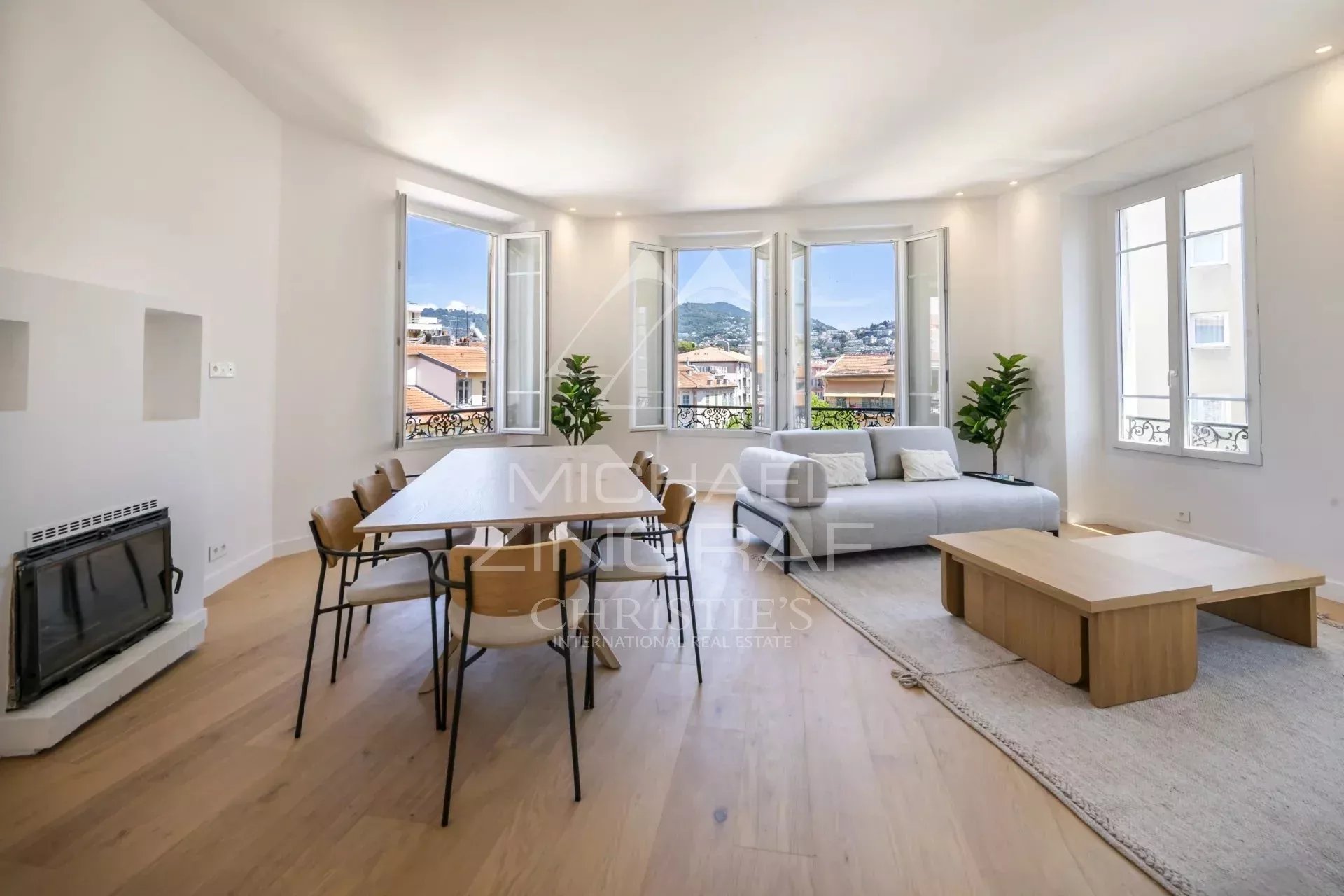 Intérieur d'un appartement spacieux avec un salon lumineux et une salle à manger, vue sur les collines.