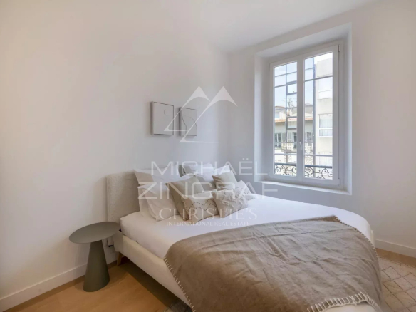 Chambre d'un appartement rénové avec lit double et fenêtre donnant sur la rue à Nice.