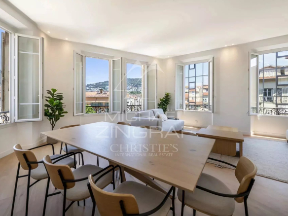 Intérieur d'un appartement spacieux avec vue dégagée, fenêtres ouvertes, mobilier moderne et table à manger.