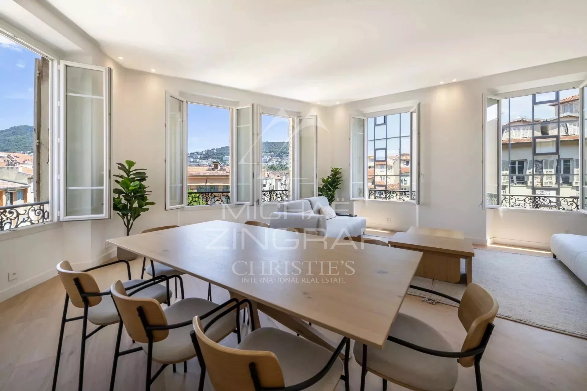 Intérieur d'un appartement spacieux avec vue dégagée, fenêtres ouvertes, mobilier moderne et table à manger.