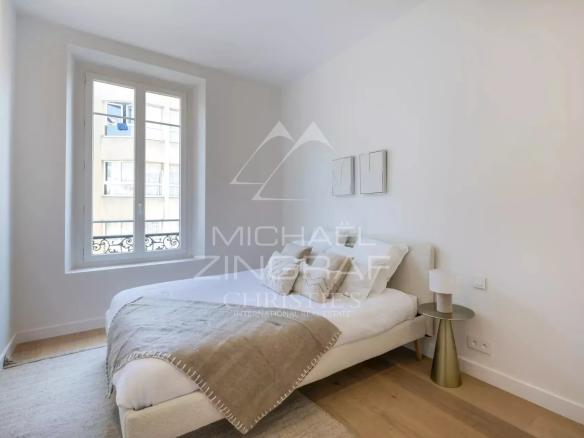 Chambre d'un appartement rénové avec un lit simple et des murs clairs.