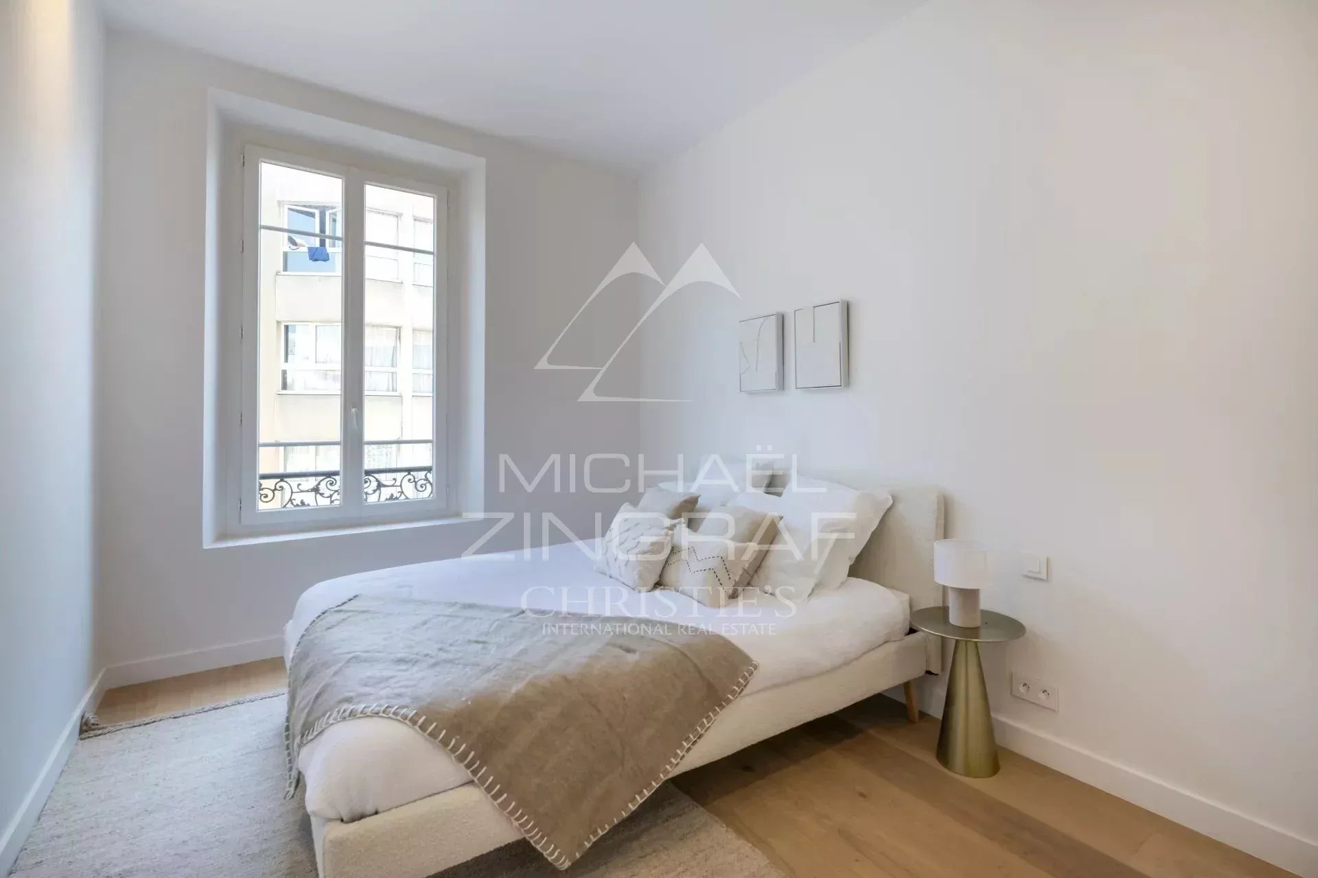 Chambre d'un appartement rénové avec un lit simple et des murs clairs.