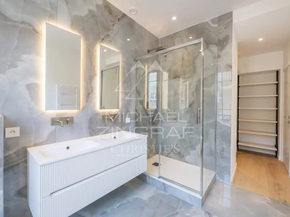 Salle de bain moderne avec douche en verre et meuble vasque dans un appartement rénové.