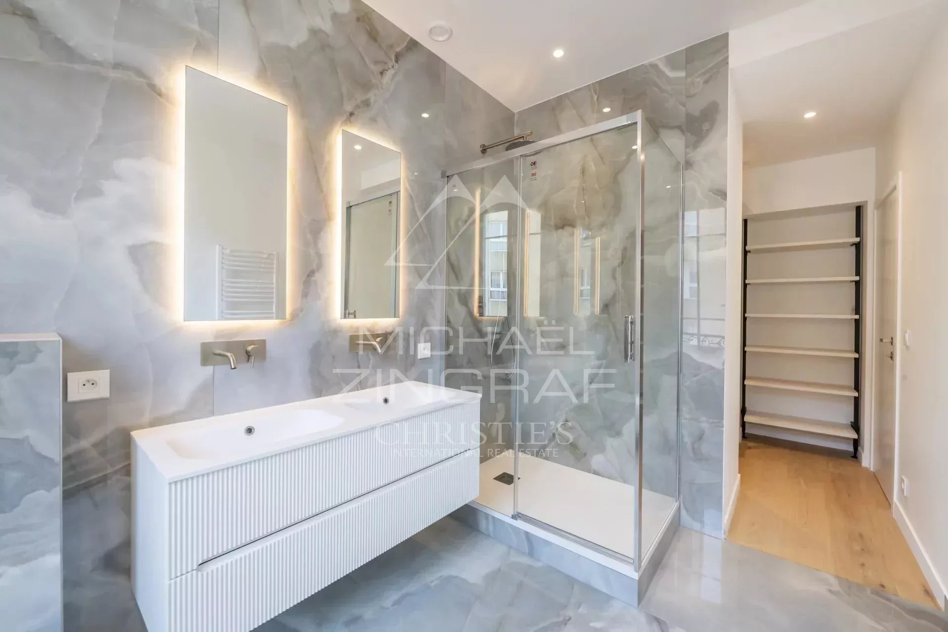Salle de bain moderne avec douche en verre et meuble vasque dans un appartement rénové.