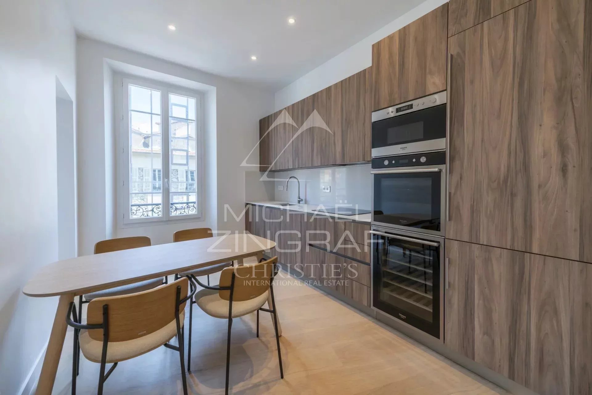 Cuisine moderne avec meubles en bois et appareils électroménagers intégrés dans un appartement rénové.