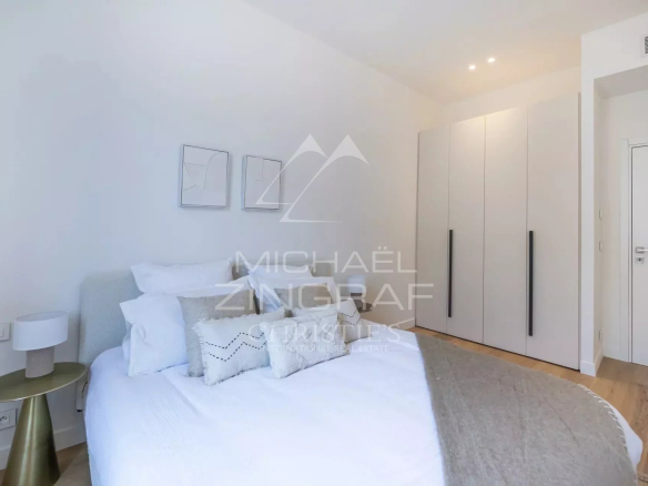 Chambre d'un appartement rénové avec lit double et placard, murs clairs et décoration moderne.
