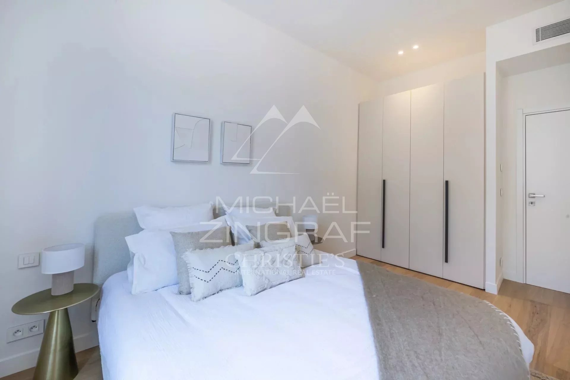 Chambre d'un appartement rénové avec lit double et placard, murs clairs et décoration moderne.