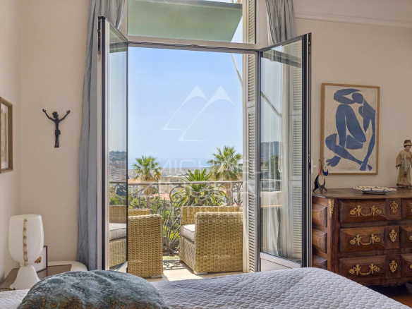 Chambre d'un appartement avec vue sur la mer à Nice, fenêtres ouvertes sur un balcon.