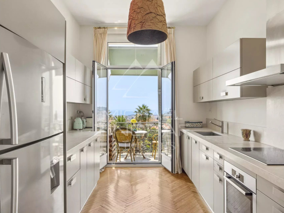 Cuisine moderne d'un appartement avec vue sur la mer à Nice, fenêtres ouvertes sur un balcon.