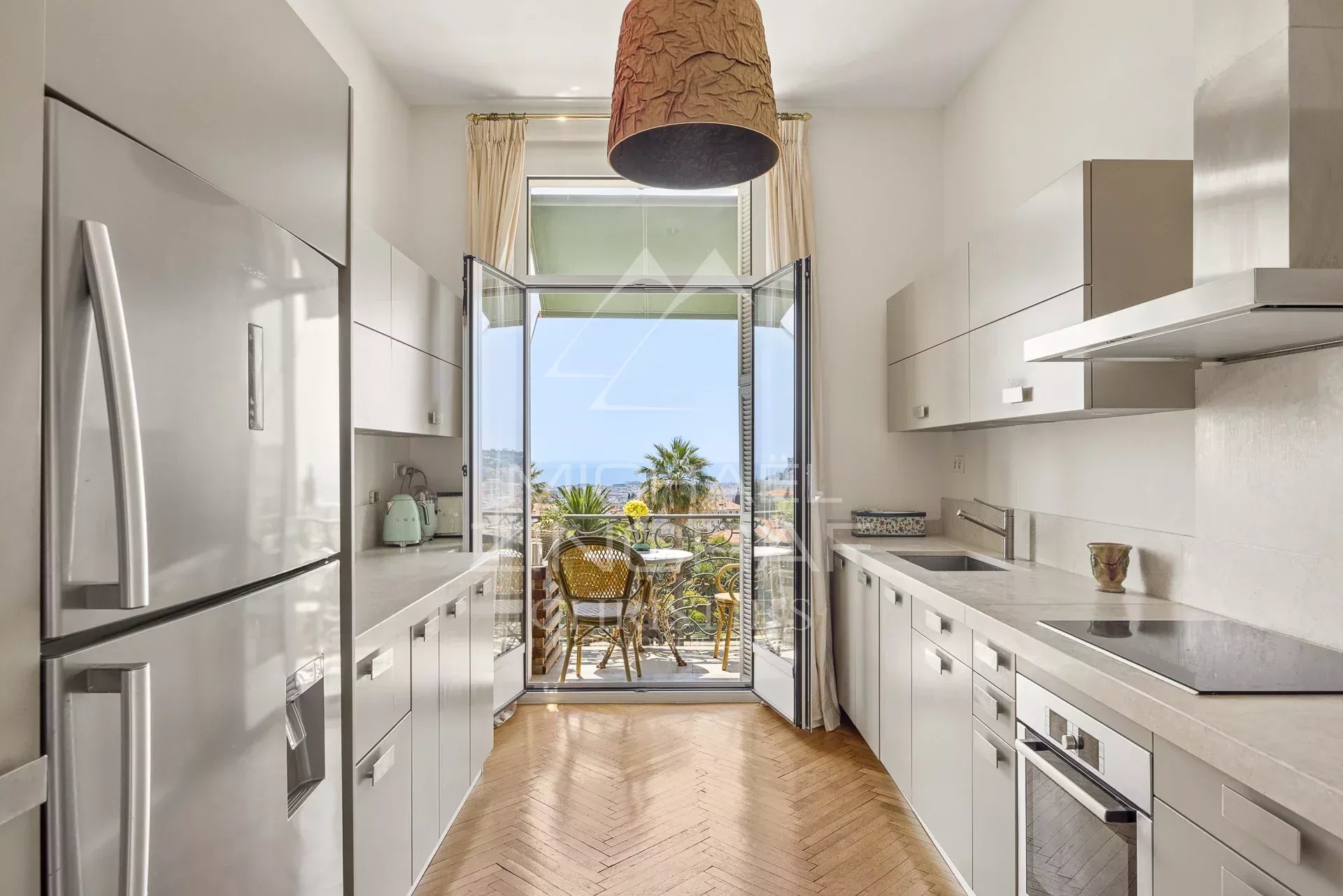 Cuisine moderne d'un appartement avec vue sur la mer à Nice, fenêtres ouvertes sur un balcon.