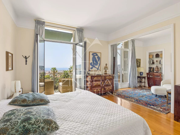 Chambre d'un appartement à Nice avec vue sur la mer et accès à un balcon.