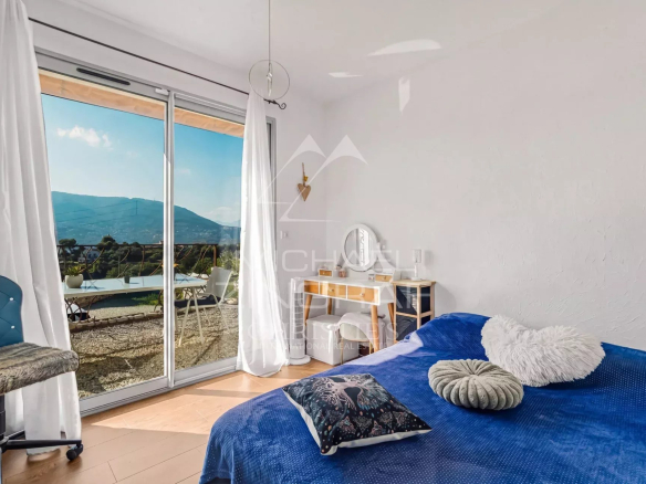 Chambre lumineuse avec vue sur les collines, accès à une terrasse, décoration moderne.