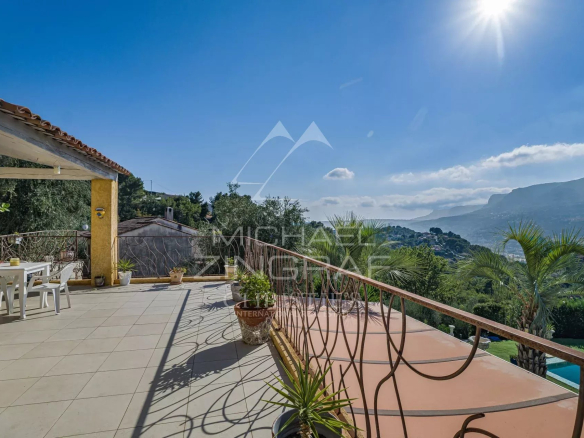 Terrasse d'une propriété à Colomars avec vue sur les collines et montagnes, piscine visible.